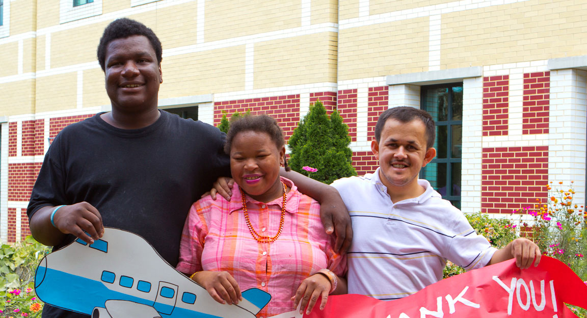 three students holding artwork