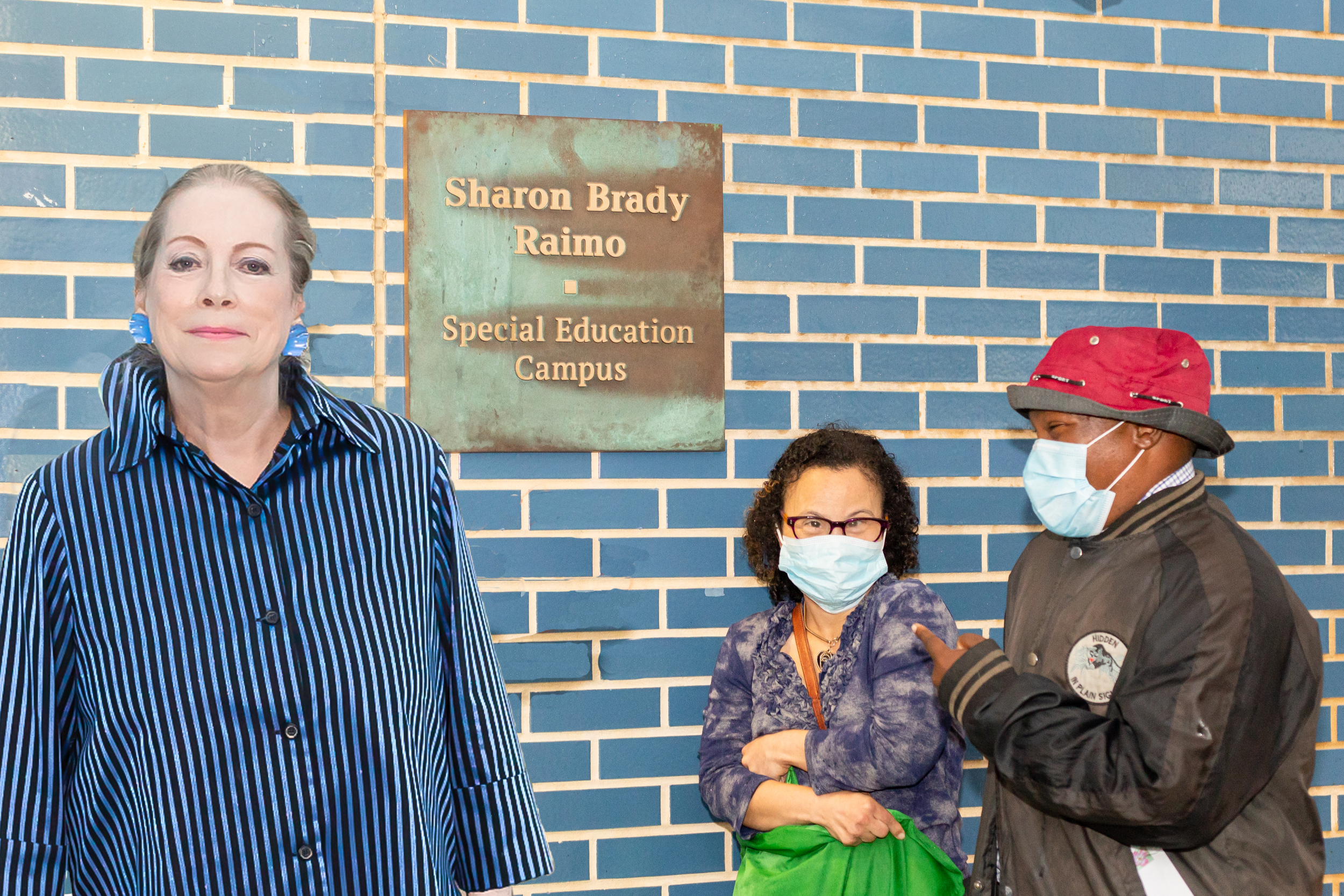 Sharon Raimo next to plaque with students in background.