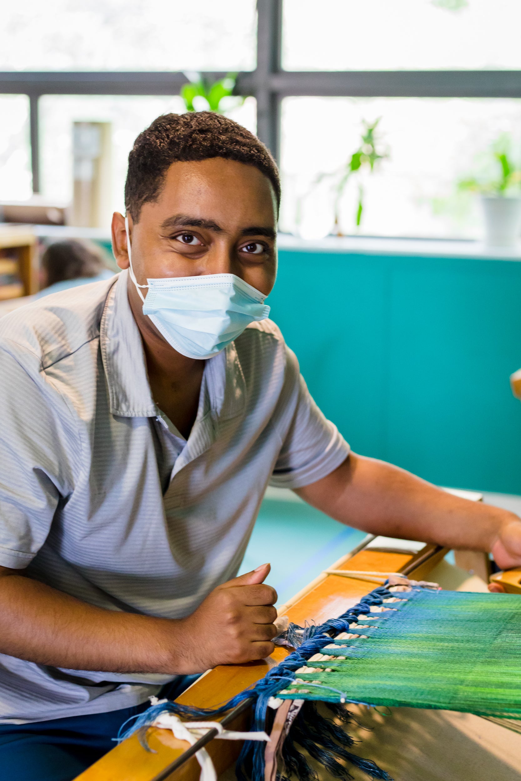 Artisan weaving at the studio wearing mask